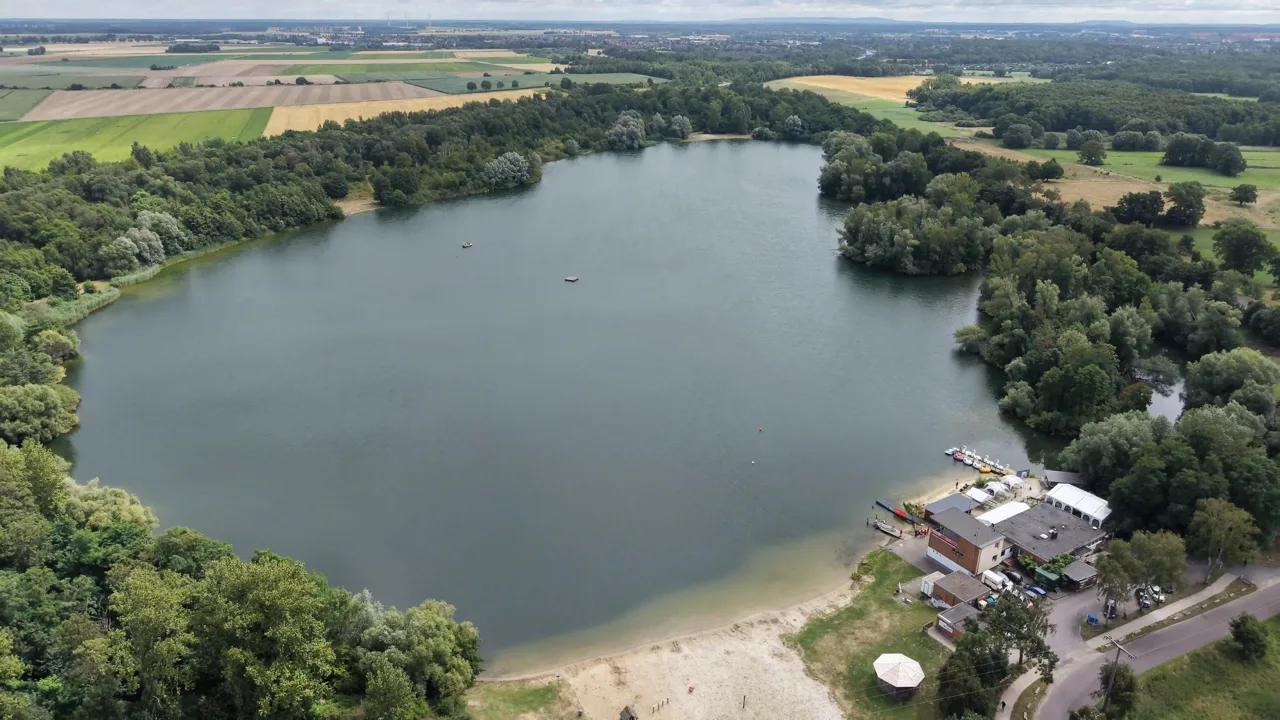 Luftaufnahme des Eixer Sees mit Sandstrand, Bootssteg und Haus am See
